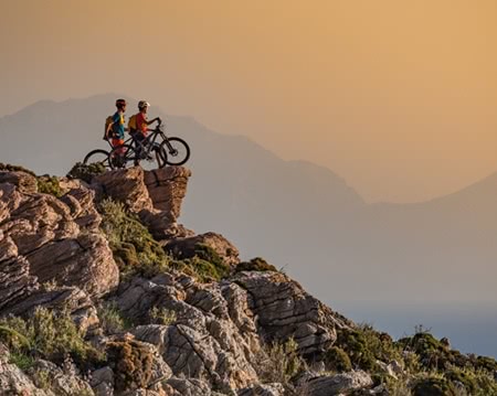 Two mountain bikers standing on a rocky outcrop